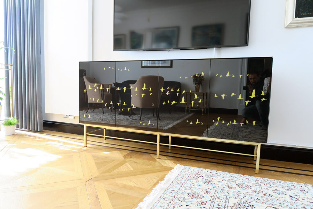 The body of this sideboard is cladded with black glass with imprints and a base made of polished brass